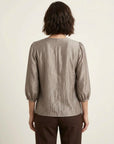 blusa-satinada-ale-gris-plata-en-modelo-vista-posterior-con-pantalon-marron